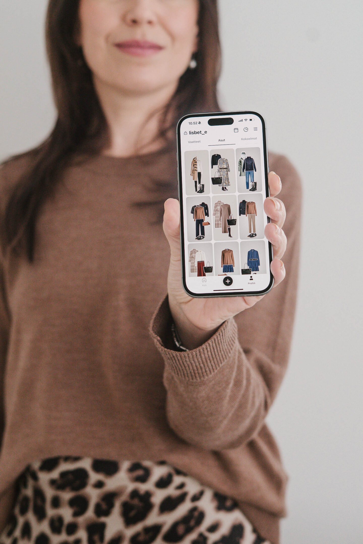 Bloggaaja pitää kädessään puhelinta, jossa on auki kapselivaatekaapin suunnitteluun tarkoitettu mobiilisovellus
