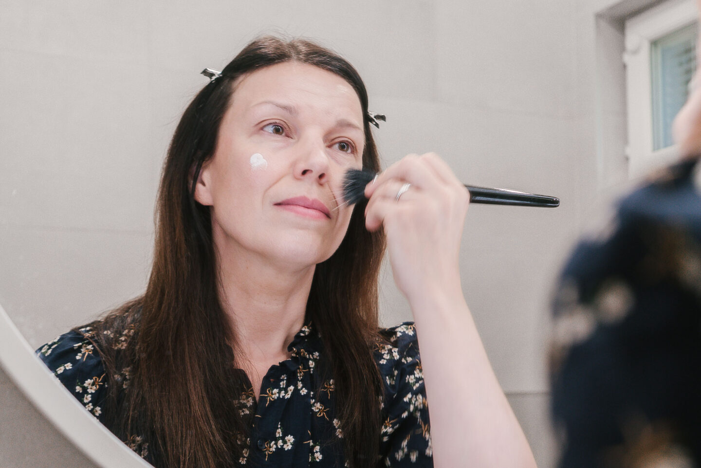 Bloggaaja levittää sävyttävää peitevoidetta siveltimellä.